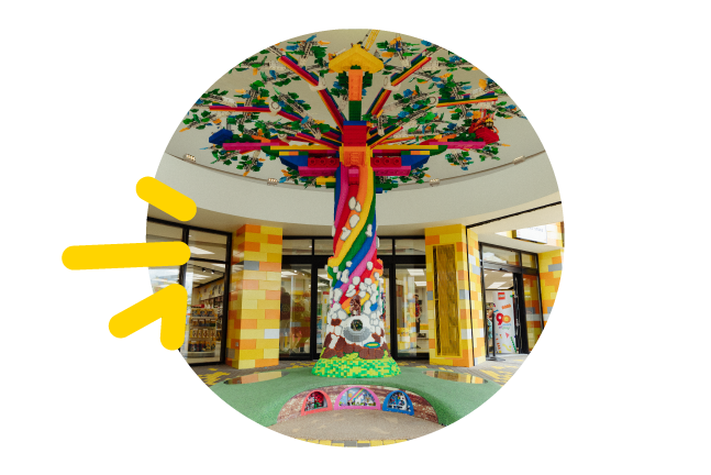 A picture bubble of a huge rainbow tree made of LEGO bricks, reaching from the floor to the ceiling of the room