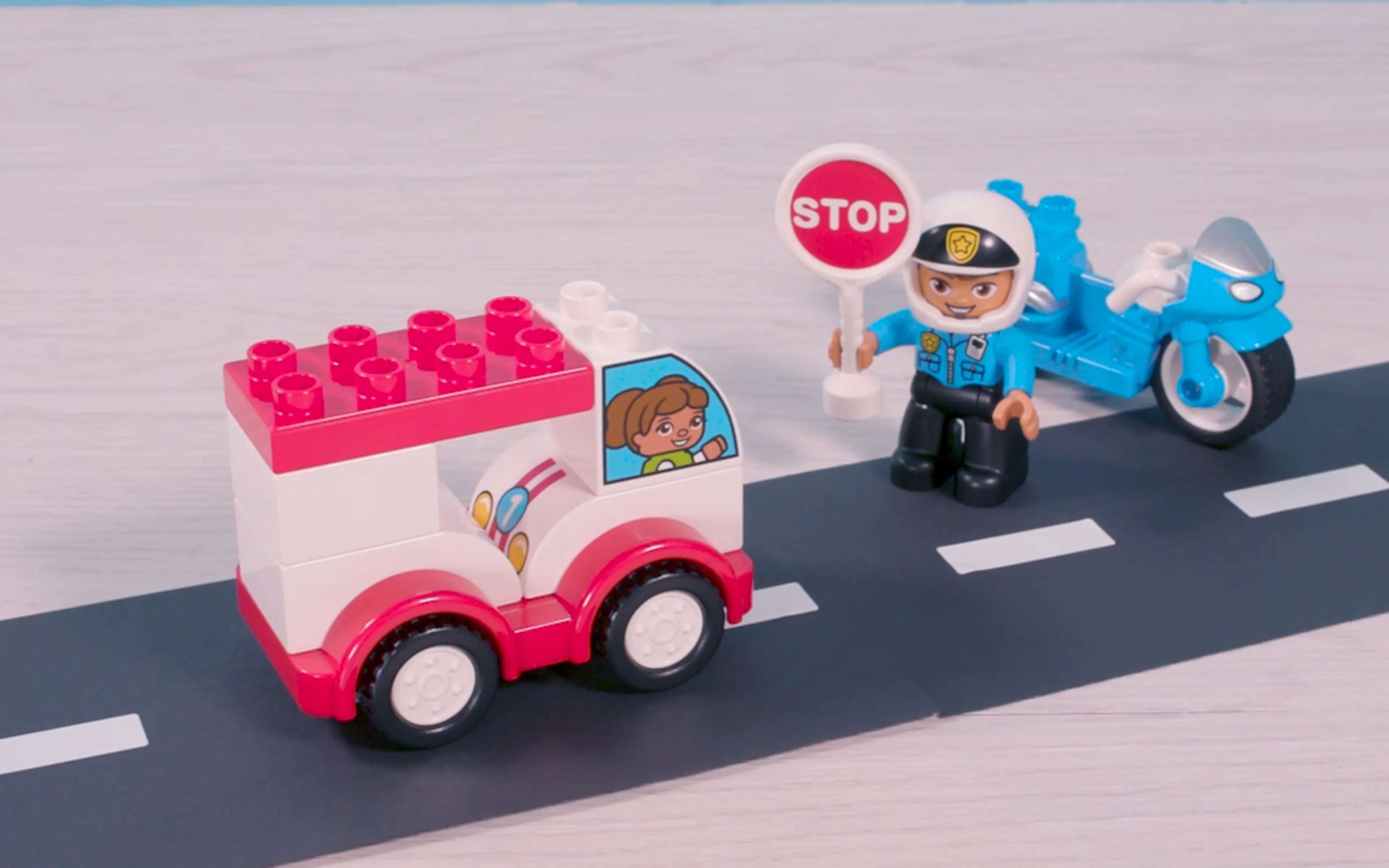 Et billede af en LEGO DUPLO politibetjent, der holder et stopskilt